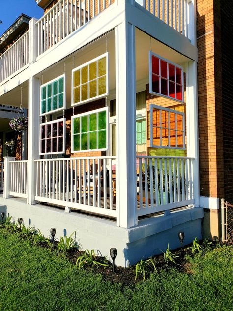 Used these windows as a psuedo privacy screen from the street to our front porch.  Bought the windows on Facebook marketplace.   Scraped the old paint off the glass.  Used Krylon Stained Glass spray paint to spray all the windows (2 cans each).   Then sealed/painted them all.   Bought the chain and eye bolt screws from home depot to hang them. Old Window Hanging On Porch, Hanging Windows On Porch, Stained Glass Privacy Screen, Front Porch Screening Ideas, Old Windows Hanging On Porch, Windows On Fence, Funky Front Porch, Stained Glass Decor Wall Hangings, Repurposed Stained Glass Windows