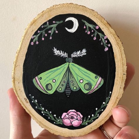 Autumn Woods Studios on Instagram: “A mini moth wood slice painting 🌙 I used to love green and pink when I was younger.. it’s a slept on color combo in my opinion 🌿🌸 . . . .…” Witchy Wood Slice Painting, Mini Wood Paintings, Log Painting Ideas, Wood Slice Painting, Wood Painting Ideas, Witchy Painting Ideas, Wooden Artwork, Painted Plant Pots, Moth Art