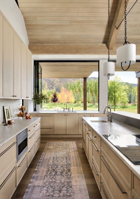 An accordion window in the kitchen opens to an exterior grilling area. Blonde-stained cabinets mimic the hue of the ceiling’s vertical-grain hemlock paneling, which continues onto the patio’s overhang for a seamless look. The runner is from Jaipur Living. Kitchen Cabinets Ceiling, Outside Breakfast, Kitchen Servery, Ceiling Window, Luxurious Home, Architecture Home, Jaipur Living, Galley Kitchen, Colorado Homes