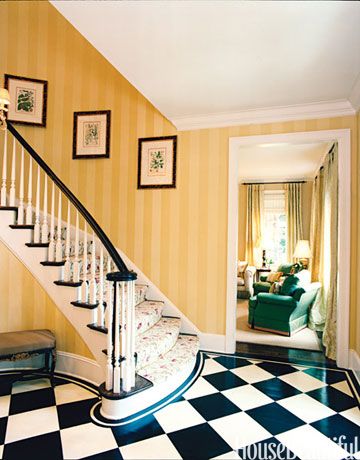 Classic checkerboard floor tiles with tone-on-tone yellow stripes on the wall say traditional. But what is the floral garden going up the stairs? Unexpected. Striped Walls Vertical, White Foyer, Checkered Floor, Foyer Staircase, Checkerboard Floor, Nina Campbell, Striped Walls, Foyer Decorating, Black And White Tiles