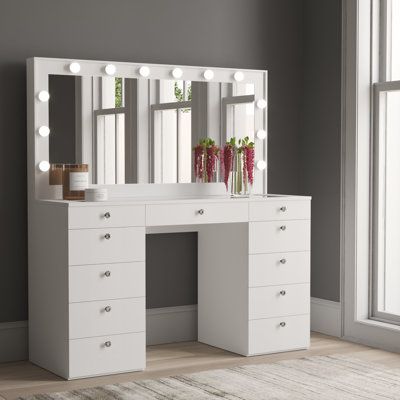 Create the ultimate glam room in your space with this lighted vanity. It features 11 drawers with crystal-inspired knobs that provide all the storage you need for beauty essentials, jewelry, and hair products. Plus, it features built-in Hollywood-style light bulbs around the mirror, allowing you to achieve your ideal look. This spacious vanity is made from engineered wood with a crisp white finish. A glam glass top adds an elegant touch. Plus, it comes with a USB port and a power outlet that let Vanity Inspo, Mirrored Vanity Table, Makeover Bedroom, Large Vanity, Make Up Desk Vanity, Lighted Mirror, Glam Room, Bedroom Vanity, White Vanity