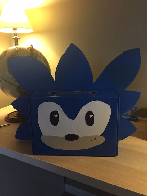 Sonic Valentine's Card Box Idea.  We cut out his hair on a separate piece of cardboard; then spray painted the shoe box and cardboard hair. Eyes, mouth and nose are all just construction paper glued on with a marker smile.  His hair is hot clued to back of the box; with the face on the front.   Turned out SUPER cute! Kids Valentine Shoe Box Ideas, Decorating Shoe Boxes For Valentines, Diy Valentine's Box For Boys, Valentines Box Ideas Creative Boys, Cool Valentines Boxes For Boys, Valentines Day Shoe Box Ideas For Boys, Sonic Valentine Box Ideas, Sonic Hedgehog Valentine Box Ideas, Shoebox Valentine Box Schools For Boys