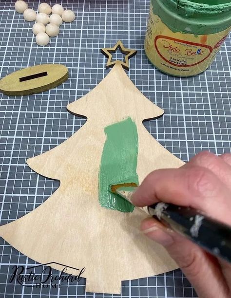 Make your own Wood Christmas Tree Décor with this simple holiday crafting idea! Paint A Christmas Tree On Wood, Painted Wood Trees Christmas Decorations, Unfinished Wood Christmas Tree, How To Paint Unfinished Wood Crafts, Painting Wood Christmas Trees, Painting A Christmas Tree On Wood, Dollar Tree Wood Christmas Crafts, Painting Wooden Christmas Trees, Painted Wood Christmas Trees