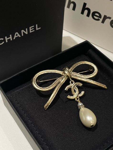 Add elegance to your look with this exquisite Chanel jewelry piece, the new Chanel 22S Bow Tie Brooch. This yellow gold plated brooch with a lustrous freshwater pearl creates a sophisticated statement in women's jewelry. A pristine example of Chanel's used jewelry, this brooch is ideal for elevating any ensemble. Its timeless design and meticulous craftsmanship make it a must-have accessory for collectors of Chanel jewelry and top-quality gold jewelry lovers. Enhance your collection today with this extraordinary piece. Tie Brooch, Chanel Jewelry, Pearl Brooch, Gold Pearl, Jewelry Lover, Bow Tie, Jewelry Pieces, Women's Jewelry, Freshwater Pearls