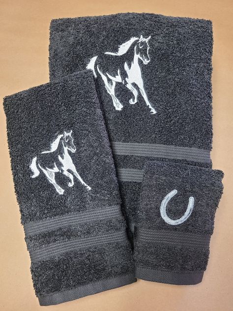 "A bath towel set that is one of our most striking,  and that will truly add some illuminating character to your bathroom. The beautiful rich black towels are embroidered with a horse in motion , in shining silver!  Not only do they look beautiful and display fine craftsmanship in a custom embroidered design, but they are also created with luxurious feeling bath towels that are soft and high quality.  Our customers often buy these for their own home decor, but also often buy them as special hous Horse Decorations, Western Bathroom Decor Ideas, Horse Bedroom Ideas, Horse Themed Bathroom Ideas, Horse Themed Bathroom, Horse Themed Bedrooms Rustic, Western Bath Towels, Horse Room Decor, Western Bathroom Decor