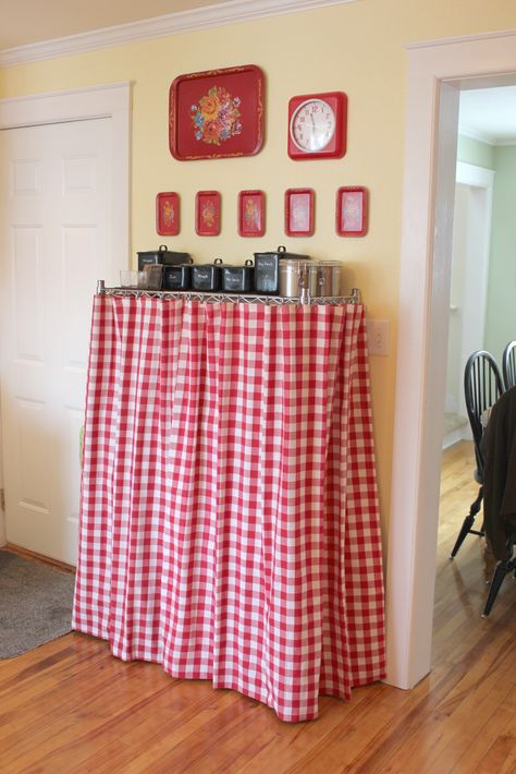 Wire Shelving Idea:  I love my wire shelving unit for the extra "pantry" storage it provides.  Even with nice storage bins and canisters, it still had a tendency to look cluttered.  These gingham "curtains" are actually 2 hemmed, square tablecloths.  They're hung on IKEA Riktig curtain clips.  (I used a plier to open the clip's attached hook, and to pinch it closed on the top wire).  Now, I don't have to look at my crock-pots, blender etc. :) Pantry Curtain, Diy Table Skirts, Desk Skirt, Gingham Curtains, Kitchen Racks, Shelf Cover, Wire Shelving Units, Shelving Ideas, Curtain Clips