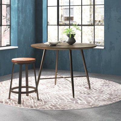 This dining table fits into most dining rooms or eat-in kitchens, while offering a sleek, modern look. Its tabletop is crafted in a circle from solid and engineered wood in a natural brown hue with an organically sloping beveled edge. The design features four steel flared legs with an X-shaped stretcher bar support, all colored in a dark brown finish. It measures about 44'' in diameter, so it's big enough to seat four people but modest enough to fit into smaller dining rooms. | Steelside™ Keith Table Wood Metal, Top Highlights, Dining Table Wood, Trestle Dining Tables, Dining Table Black, Table Wood, Small Dining, Solid Mango Wood, Breakfast Nook