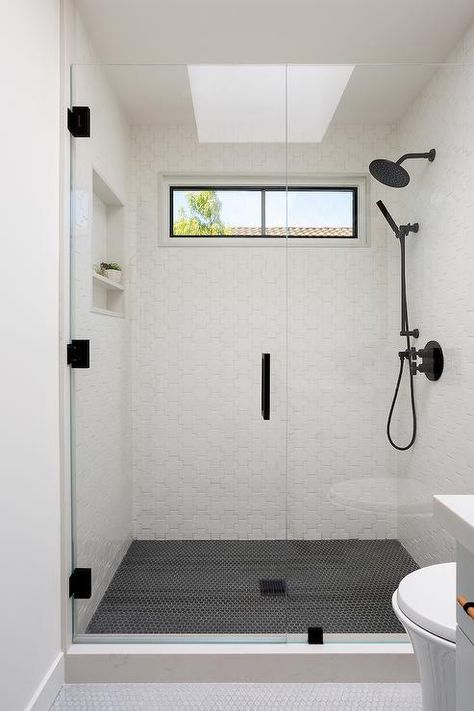 Spacious floor lever shower features white puzzle tiles with a matte black shower kit, a shower skylight and black hexagon shower floor tiles. Black Tile Shower Floor, Black Hexagon Shower Floor, Hexagon Shower Floor Tile, Hexagon Shower Floor, White Tile Bathroom Floor, Shower Floor Tiles, Shower Skylight, Frameless Glass Doors, Black Floor Tiles