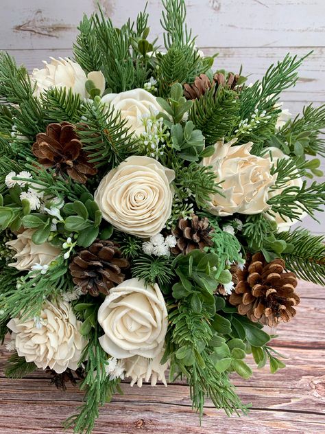 "---Wild Pine and Ivory Bouquet --- This bouquet features several types of wood roses in their natural colors of ivory along with faux pine, cedar, boxwood, baby's breath and pine cones. Flowers are handmade, which means each is unique in shape and size. Each also has variations from the wood grain and may include small flecks of bark. Flowers have beautiful and unique imperfections, as real flowers do, giving your bouquet an elegant rustic look. Custom colors are available! See our color chart Pine Cone Bridal Bouquet, Rustic Greenery Bouquet, Pine Bough Wedding Decor, Pine Cones Wedding Decor, Pine Tree Themed Wedding, Pine Color Wedding, Pine Cone Wedding Centerpieces, Pine Wedding Decor, Cedar Bouquet