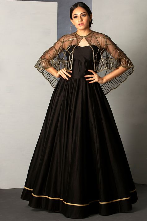 Featuring a jet black cape gown in Chanderi Silk and tulle base with pipe embroidery.  FIT: Fitted at bust. COMPOSITION: Chanderi Silk, Tulle. CARE: Dry clean only. Cape Dress Indian Gowns, Cape Gown Indian, Cape Dress Indian, Cape Dresses, Black Anarkali, Golden Gown, Gown Indian, Net Gowns, Embroidered Cape