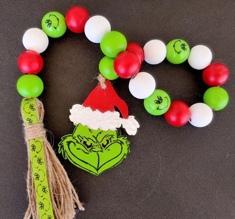 "Hello and Welcome to sewingandcraftsshop Something utterly charming has arrived! This beautiful Grinch Christmas wood bead garland will fit right in with your farmhouse country décor. Hand-painted wood farmhouse style beads in a variety of mix of green, white and red along with a Christmas Grinch wood cutout.  The tassel is made of jute twine and ribbon. The wood beads and Christmas Grinch are Hand-painted by me. This farmhouse-style strand of beads is just the right amount of lovely for your w Grinch Wood Cutout, Grinch Christmas Garland, Grinch Garland, Wood Bead Garland Christmas, Christmas Wood Bead Garland, Library Christmas, Grinch Decor, Christmas Tiered Tray Decor, Beads Garland