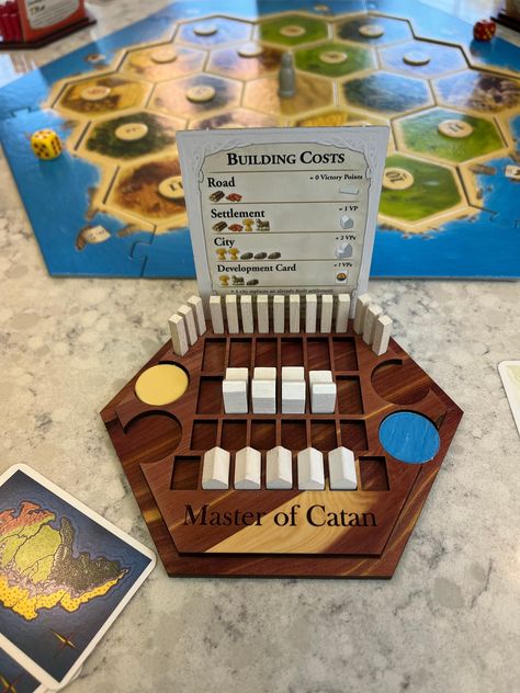 "Catan game piece holder/tray. Lazer cut from walnut plywood and finished with a clear coat for protection. Trays are designed to hold all road and buildings for the standard game. There are additional spaces for expansion sets. You are purchasing ONLY the tray. Game pieces and board are NOT included. This is just for the trays.  Trays ship STANDARD with the \"Master of Catan\" engraved on it. Custom engraving available 2.00 per tray). Discounts available for 4+ trays." Custom Catan Pieces, Custom Catan Board, Wood Board Games, Catan Game, Harry Potter Monopoly, Catan Board Game, Custom Board Games, Catan Board, Walnut Plywood