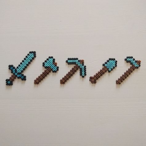 Diamond sword and tools from the game Minecraft. Made with Artkal C mini fuse beads. Read more about it on my DeviantArt page deviantart.com/ThisThatWithCat Minecraft Tools, Diamond Armor, Birthday Shirt Ideas, Minecraft Beads, Minecraft Diamond, Hamma Beads Ideas, Easy Perler Bead Patterns, Pixel Beads, Pearl Beads Pattern