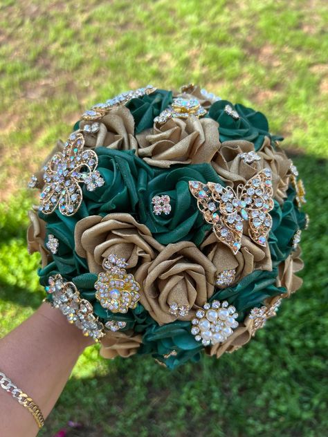 Handmade Quinceañera Bouquet/ Wedding.  With Emerald Green and Gold Roses. Finished off with Gold brooches and Butterflies.  *Please note brooches can change in style due to availability.* Decor / color combinations can be changed upon request. {This is a made to order Bouquet} Emerald Green And Gold Quince Bouquet, Emerald Green And Gold Wedding Bouquet, Emerald Green And White Quince Dress, Green Gold Quinceanera Dresses, Quinceanera Ramos Emerald Green, Wedding Bouquets Bride Emerald Green, Emerald And Gold Wedding Dress, Green And Gold 15 Theme, Emerald Green Quince Flowers