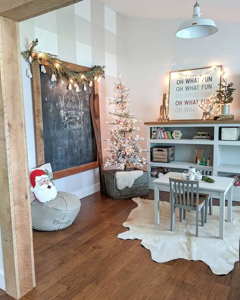 This neutrally decorated playroom is furnished with a white craft table and a matching white storage shelf with a raw wood tabletop. The shelves hold various books and toys, while the top is decorated with small holiday accent decor and string lights. Playroom Farmhouse, Rustic Playroom, White Ladder Shelf, Creative Toy Storage, Farmhouse Playroom, Playroom Organization Ideas, Toy Storage Ideas, Toy Room Organization, Playroom Shelves