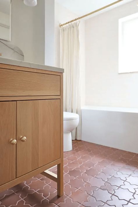 a modern white bathroom with a tub and a window, a terracotta tile floor, a stained vanity and white appliances Terracotta Tile Bathroom, Star And Cross Tile, Modern Mediterranean Bathroom, Bathroom With A Tub, Cross Tile, Terracotta Tile Floor, Herringbone Tile Floors, Modern White Bathroom, Terracotta Tile