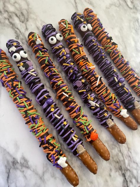 12 Halloween pretzel sticks covered in milk chocolate and Halloween sprinkles.  *note sprinkles will vary depending on availability. All sprinkles used are halloween theme.  **Important chocolate is particularly heat sensitive. High temperatures can cause the chocolate to melt and affect the decorative elements we've carefully prepare. Chocolate Covered Pretzels Aesthetic, Halloween Pretzel Rod Ideas, Halloween Themed Pretzel Rods, Chocolate Dipped Pretzels Halloween, Halloween Candy Homemade, Halloween Chocolate Pretzels, Halloween Candy Melt Ideas, Chocolate Dipped Halloween Treats, Halloween Pretzel Sticks