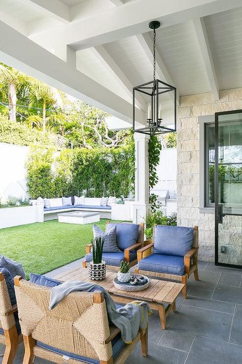 An oil rubbed bronze lantern hangs from a covered patio ceiling over a teak slatted coffee table flanked by side-by-side teak and rope chairs placed on slate pavers and matched with blue cushions. Brooke Wagner Design, Brooke Wagner, Outdoor Lounge Area, Trendy Home, Raised Beds, Outdoor Rooms, Residential Design, Patio Furniture Sets, Lounge Areas