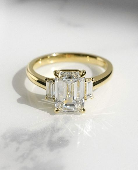 2.93 TC Elongated Emerald Cut Moissanite Trilogy 14k Solid Yellow Gold Baguette Cut Sides Gorgeous 4 Claws Three Stone Ring Anniversary Gift ❤ ITEM DETAILS:- ✦ Brand: The American Gold House (TAGH) ✦ Handmade, high-quality item! ✦ Material: Solid 10K/14K/18K Gold, 950 Platinum and 925 Sterling Silver ✦ Diamond Type: Moissanite Diamond ✦ Diamond Cut: 6.5x9 MM Elongated Emerald ✦ Width of Band: 1.8 MM (Bottom) ✦ Diamond Clarity: VVS/VS ✦ Center Diamond: 6.5x9  MM 2.45 CT Elongated Emerald ❤ SIDE STONES:-  ✦ 2 X 0.24 CT Straight Baguettes Cut Colorless Moissanite                                                                                                                                                                            -------------------------------------------------------------- Three Stone Emerald Cut Ring, Emerald Cut Engagement Ring, Emerald Cut Engagement, Emerald Cut Moissanite, Emerald Cut Rings, Three Stone Ring, Emerald Engagement Ring Cut, Stylish Rings, Baguette Cut