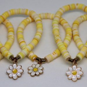 Clay bead bracelet with multiple colors of yellow beads and 2 gold spacer beads with a daisy charm in the middle Clay Bracelet Ideas, Clay Bead Bracelet, Yellow Bracelet, Daisy Charm, Daisy Bracelet, Yellow Daisy, Clay Bracelet, Clay Bead, Bracelet Ideas