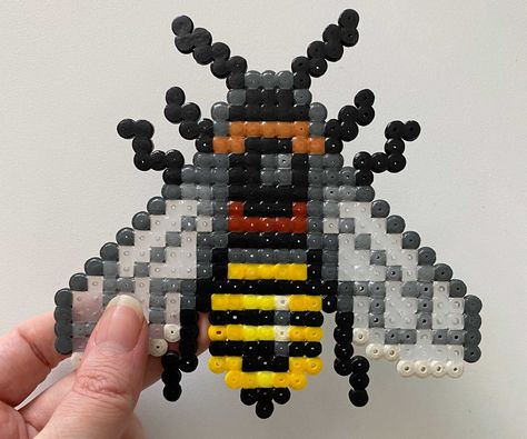 Make this pretty perler bead honeybee with transparent wings! This template consists of one pattern for how to make the honeybee. This item is a DIGITAL DOWNLOAD only, it does not contain any physical product, only templates for how to make the honeybee that you can print at home. The download consists of two PDF's of the same pattern, one in A4 format and one in Letter format. The patterns are designed to be printed in color at 100% to make sure that the print is the correct size in order to be Perler Bead Insects, Bee Hama Beads, Perler Patterns Cute, Roblox Perler Bead Patterns, Football Perler Bead Patterns, Perler Bead Patterns Hexagon Board, Legendary Pokemon Perler Bead Patterns, Bug Perler Beads, Perler Bead Pins