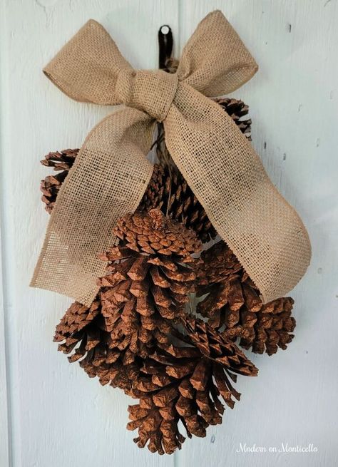 Pine Cone Door Swag, Pine Cone Door Hanger, Pine Cone Swags, Fall Pine Cone Decorations, Pinecone Swag Diy, Decor With Pinecones, Gold Glitter Spray Paint, Glitter Door, Lake Christmas