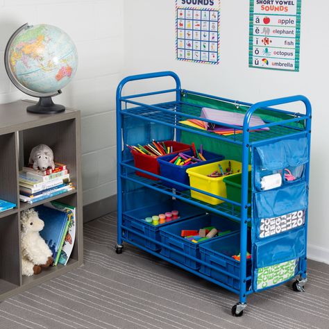 "The perfect accessory for any classroom, this all-purpose teaching cart provides plenty of pockets and bins to store all of the teaching essentials. Steel frame is durable and casters lock in place for stability. The perfect accessory for any classroom, this all-purpose teaching cart provides plenty of pockets and bins to store all of the teaching essentials. Side pockets on either edge allow for easy storage of writing utensils, flash cards and other small items while the bins in the center ho Organizing School, Craft Storage Cart, Cubby Bins, Organization Cart, Arts And Crafts Storage, Teacher Activities, Classroom Storage, Writing Utensils, Rolling Storage