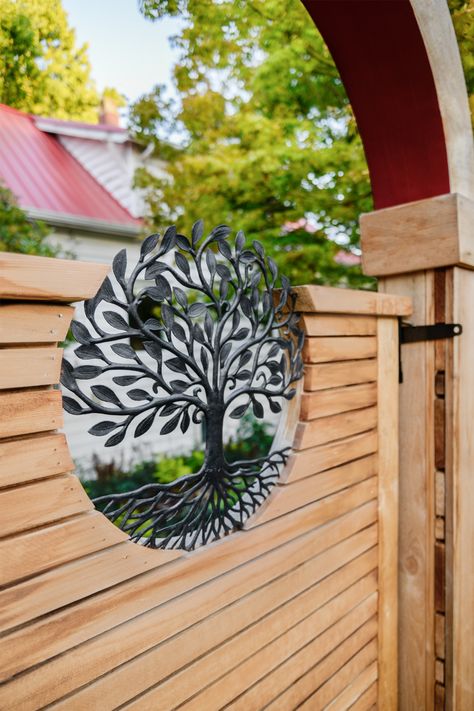 A tree of life emblem accents a custom wood gate. #treeoflife #fence #gate #customfence #landscapedesign #boardandvellum Tree Of Life Gate, Circle Gate Design, Garden Gate Ideas, Patio Gates, Amazing Gates, Gardening Design Diy, Metal Garden Gates, Garden Gate Design, Fence Gate Design