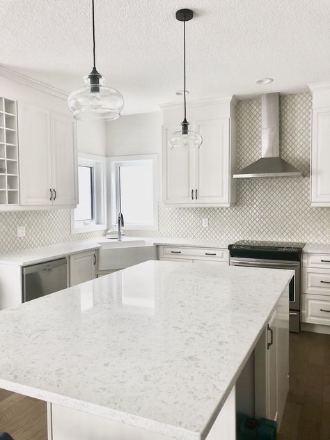 This blend of whites and creams is the perfect combination for anyone who wants a timeless and classic kitchen. #whitekitchen #creamkitchen #whitequartzcountertop #apronsink #whitecabinets #creamcabinets #antiquecabinets #pewterhandles #brightkitchen #farmhousekitchen #highdesignkitchen #arabesquetile #teardroptile #creamtile #raisedpanel #traditionalkitchen #contemporarykitchen #whitewalls #whitecountertops #blackpendants #vintagelights #openconcept #largeisland #marianneelizabethdesign Kitchen White Countertops, Creamy Kitchen, Mosaic Backsplash Bathroom, Cream And White Kitchen, Teardrop Tile, Tailor Design, White Effect, Beach Style Kitchen, Black Cabinet Handles