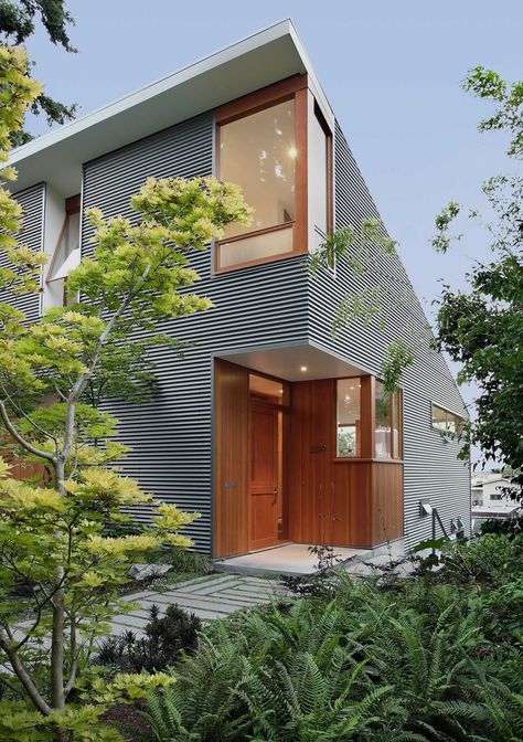 A modern house with corrugated metal siding and a wood front door and window frames. Home Siding Ideas Exterior, Metal Siding House, Shed Architecture, Corrugated Metal Siding, Modern Contemporary Homes, Metal Cladding, Seattle Homes, House Shed, Wood Architecture