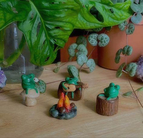 Three clay frogs gathered around a campfire: one roasting a marshmallow, one sitting on a log, and one playing the guitar Clay Campfire, Fairy Caravan, Clay Artwork, Campfire Songs, Clay Sculpting, Around The Campfire, Roasting Marshmallows, Clay Wall Art, Fire Clay