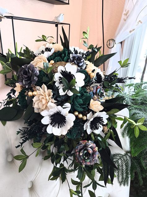 This beautiful wooden flower cascade features gorgeous sola wood flowers in dark green, black, and champagne.  Beautiful faux and preserved greenery fill out this cascade.  Pictured bouquet features comic book flowers - select from the drop down menu to choose to have these left out or use book flowers instead. Bouquet measures 10+ inches across at the top and is 16-18 inches long. For customization, send me a message to discuss. :) To purchase matching boutonnieres, look here: https://www.etsy.com/shop/mydinosaurdreams/?section_id=21264911 To purchase matching corsages, look here:  https://www.etsy.com/shop/mydinosaurdreams/?section_id=21264913 **Sola Flowers** *Sola flowers are hand-made from a soft wood (similar to balsa) and as such, each is unique!  They feel similar to thick, spongy Comic Book Flowers, Comic Book Bouquet, Glam Wedding Bouquet, Flower Cascade, Bouquet Cascade, Book Bouquet, Witchy Wedding, Wooden Flower Bouquet, Teardrop Bouquet