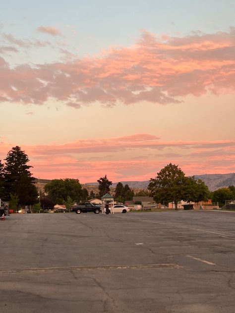 A picture of a old school parking lot with a few cars in it. And the Sunset is slowly setting in the background. With the sky transitioning from light blues to pinks and orange. With fluffy white clouds dancing in the sky. Seatac Washington, Prettiest Sunsets, Sunnyside Washington, Washington Scenery, Washington Dc Sunset, Chelan Washington, 2024 Era, Chasing Sunsets, The Top