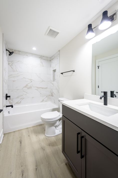 Check out this contemporary bathroom we just finished! 🛁✨ With sleek marble tiles, cool black fixtures, and warm LVP flooring. it’s the perfect blend of style and comfort.  #CustomHomeBuilder #BathroomGoals #LuxuryLiving #HomeInspo  @bobbi_lambros-designs @cat_3_photography Marble Bathroom With Black Fixtures, Lvp In Bathroom Floor, Bathroom With Lvp Flooring, Lvp In Bathrooms, Lvp Bathroom Floor, Lvp Bathroom, Black Fixtures, Rental Ideas, Toilet Vanity