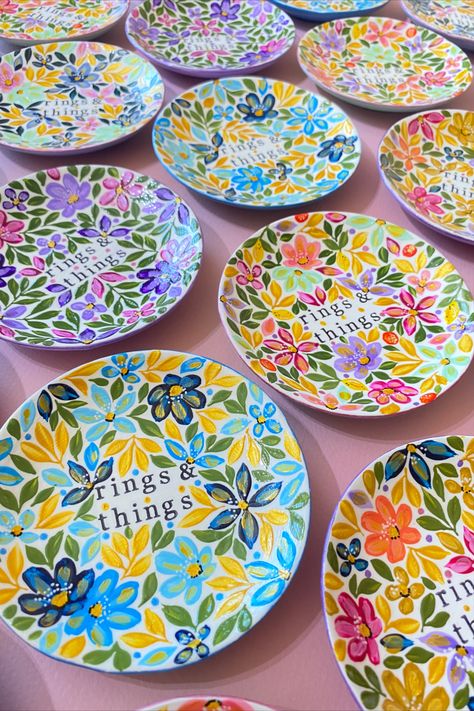 A variety of colourful floral ceramic trinket dishes with rings & things wording on pink background Pottery Painting Ideas Trinket Dish, Pottery Painting Trinket Dish, Trinket Dish Painting Ideas, Painted Catch All Dish, Hand Painted Trinket Dish, Hand Painted Ring Dish, Ceramic Jewelry Dish, Jewelry Dish, Ceramic Jewelry