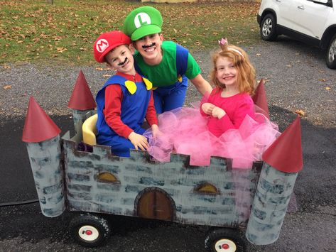 Mario, Luigi, and Princess Peach with the castle built over a wagon Castle Wagon Halloween, Mario Cart Halloween Wagon, Mario Wagon Halloween, Princess Wagon For Halloween, Mario Wagon Costume, Mario Luigi And Princess Peach Costumes, Halloween Wagon Decor, Mario Luigi Princess Peach Costume, Wagon Halloween Ideas