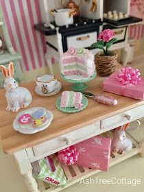 Easter has hopped its way into the miniature dollhouse.  It's on the   island in the kitchen.             It's on the fireplace mantel.... Island In The Kitchen, Easter Dollhouse, Room Box Miniatures, Miniature Inspiration, Tree Cottage, Miniature Bakery, Happy Easter Wishes, Ash Tree, Doll Diy