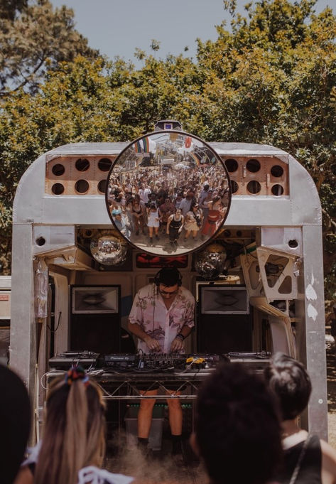 A DJ performing live inside a retrofitted mobile venue with a large crowd reflected in a circular mirror. Green Palace, Dj Performance, Outdoor Movies, Silent Disco, Bar Setting, House Parties, Stall Designs, Coffee Club, Festival Decor