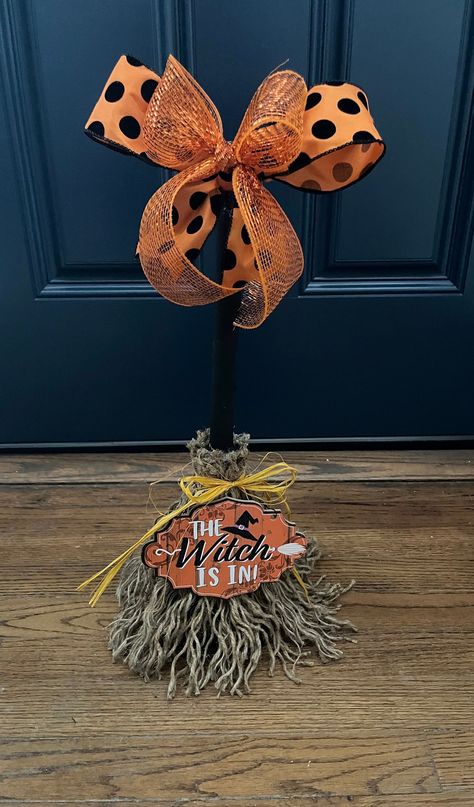 This adorable Witch Broom is all treats and no tricks! A duo of bows sit  atop of a black hand painted broom handle. Jute rope is used as bristles, it is unraveled by hand and attached to the handle. A yellow raffia bow ties up the broom while a sign announcing The Witch Is In sits bottom center of this cute broom! Unique and cute this broom will have you swept away in no time!! Made to order  For decorative purposes only Witch’s Broom, Witch Broomstick Diy, Fall Broom, Witch Brooms, Halloween Brooms, Witch Bells, Witches Broomsticks, Witches Broom, Creepy Halloween Decorations