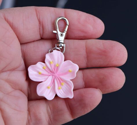 **THIS IS A RESIN CHARM. This sweet little hibiscus zipper charm was just too hard to pass up! The flower is light pink resin, and a perfect accent for a jacket, backpack, laptop bag, luggage, cosmetic bag, purse, planner, wallet, or gym bag.  Makes a great little gift for the hibiscus lover or gardener. Quality and detail is very nice.  Charm is one-sided. Lobster clasp  9mm x 23mm. Clasp base swivels 360 degrees. *INTENDED FOR AGES 12 AND UP. Hibiscus Flower Keychain, Cute Pink Keychain, Aesthetic Clay Charms, Hibiscus Keychain, Girly Keychains, Planner Wallet, Backpack Charms, Pink Gift Ideas, Pink Keychain