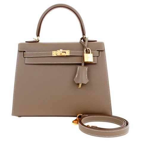 This authentic Hermès Etain Madame 25 cm Sellier Kelly is pristine with the protective plastic intact on the hardware. Designed with the stitching on the outside of the bag, the Sellier silhouette has a more structured appearance than the Retourne version. Demure and streamlined Sellier Kelly is neutral and wearable in grey Etain with warm gold hardware. Chevre leather interior and protective footed bottom. Carried by the top handle or with the optional strap. Padlock, keys, clochette, strap and Hermes Kelly 25 Outfit, Hermes Clothes, Kelly Bags, Hermes Kelly 25, Kelly 25, Dream Bags, Hermes Kelly Bag, Middleton Style, Girly Bags