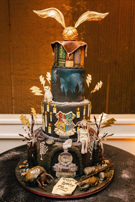 Four tiered birthday cake decorated with Harry Potter themed items topped with gold wings Birthday Party Harry Potter, Harry Potter Inspired Birthday, Louise Cake, Sweet Sixteen Party Ideas, Event Decor Table, Harry Potter Theme Birthday Party, Hogwarts Birthday, Harry Potter Theme Cake, Harry Potter Themed Birthday