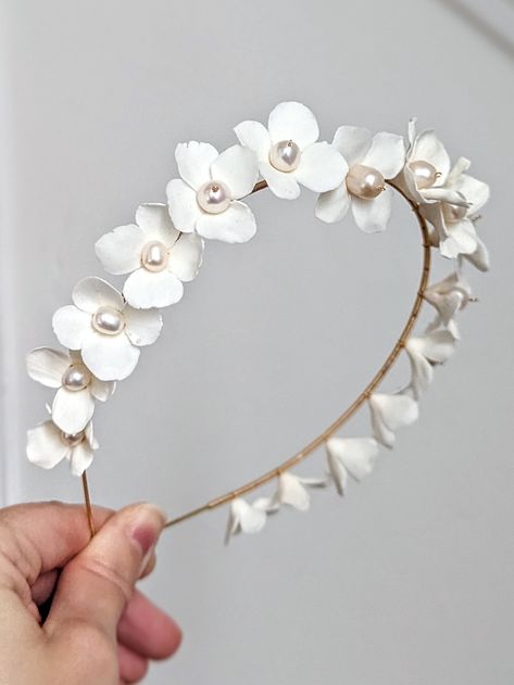 This beautiful bridal headband is made with intricately hand-crafted ivory/white clay wild blooming flowers. Each flower is embellished with gorgeous luster Swarovski pearls and genuine freshwater pearls. Attached to the gold headband base. Due to the handmade nature of each accessory, please handle it with care. Matching Items: HAIR ACCESSORIES: https://www.etsy.com/uk/listing/1586752880/floral-bridal-headpiece-porcelain-flower https://www.etsy.com/uk/listing/1610068447/wedding-hair-accessories Bridal Floral Headpiece, Wedding Hairpiece, Floral Tiara, Headband Wedding, Crown Wedding, Flower Crown Wedding, Floral Headband, Gold Headband, Modern Bridal