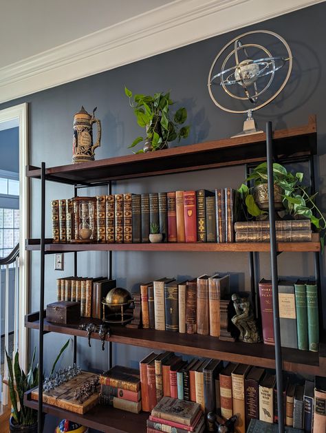 Wall color is apparently "Sherwin Williams Outerspace". Bookcase is apparently "the Beckett Storage Bookshelf from Crate and Barrel". Image originally uploaded at: https://old.reddit.com/r/AmateurRoomPorn/comments/16ju6pj/living_room_with_a_moody_whiskey_bar_vibe_in/ Whiskey Lounge, Living Room Shelf, Storage Bookshelf, Room Shelf, Bookcase Styling, Whiskey Bar, Book Room, Living Room Shelves, Book Shelves