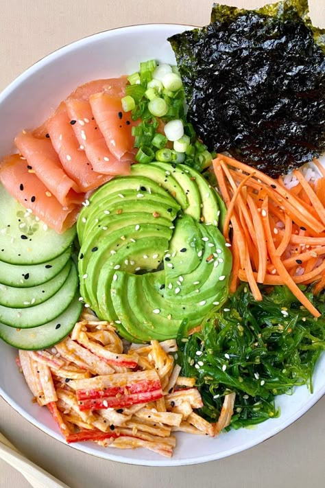 sushi bowl with smoked salmon, spicy mayo crab salad, avocado, cucumber, seaweed, carrots, green onions, and roasted seaweed over white rice and served in a white bowl with a pair of chopsticks Yummy Bowls, Crab Sushi, Salad Bowl Recipes, Sushi Bowl Recipe, Sushi Bowls, Sushi Salad, Easy Sushi, Diy Sushi, Poke Bowls