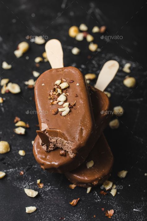 Chocolate ice cream popsicles by its_al_dente. Milk chocolate popsicles with hazelnuts. Close-up. Ice cream popsicles covered with chocolate, sticks, black stone ba... #Sponsored #its_al_dente, #Milk, #chocolate, #popsicles Chocolate Popsicle, Popsicle Chocolate, Chocolate Fudge Popsicles, Cookies And Cream Popsicles, Popsicle Photography Food Styling, Chocolate Popsicles, Ice Cream Factory, Belgium Chocolate, Ice Cream Popsicles