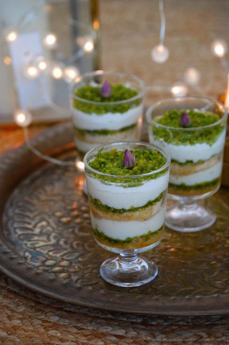 A layered Middle Eastern dessert, Aish el Saraya which contains layers of powdered rusk soaked in sugar syrup, an eggless creamy custard, pistachios and thick cream. This would be the perfect dessert to serve during Eid. We love desserts! And if it is Arabic sweets, we love them even more. You all must be awareRead more Arabic Desserts Middle East, Moroccan Dessert Recipes, Eid Desserts, Eid Dessert Recipes, Cups Recipes, Arab Food, Arabic Sweets Recipes, Lebanese Desserts, Arabic Desserts