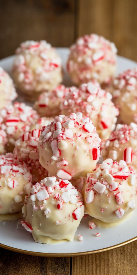 Embrace the holiday spirit with these delightful Peppermint Bark Snowballs! Soft, chewy, and packed with chocolatey goodness, these snowy treats are coated in a sweet white chocolate and sprinkled with crushed candy canes for the perfect festive touch. No Bake Peppermint Snowballs, White Chocolate Peppermint Truffles, Snowman Treats For School, White Peppermint Bark, Xmas Sweet Treats, Holiday Treats To Make With Kids, Peppermint Balls Christmas, Peppermint Christmas Candy, Individual Christmas Treats