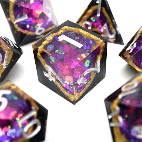 Regal Relic Crystalline Geode Dice: 7-Piece Set Embark on your Dungeons and Dragons adventures with the Regal Relic Crystalline Geode Dice set, designed to invoke the mystique and majesty of ancient treasures. Each die in this exquisite set features a polished surface that reveals an amethyst-coloured geode, resplendent against a stark black background and luxuriously edged in gold. This opulent combination not only enhances the visual appeal of your gameplay but also resonates deeply with the epic themes and characters encountered in DnD. Striking Visual Features The Regal Relic dice set showcases amethyst-coloured geodes, known for their rich, deep purple hues that suggest both royal lineage and arcane power. The contrast provided by the black backing intensifies the vibrant purple, maki Dnd Aesthetic Dice, Resin Dice Ideas, Cool Dnd Dice, Pretty Dice, Geode Crystals, Dungeons And Dragons Adventures, Dice Goblin, Dungeons And Dragons Dice, Dnd Dice