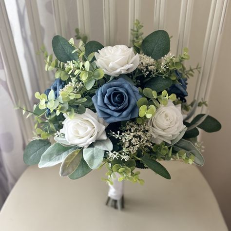 "Boho bridal bouquet, steel blue  & white roses with greenery wedding bouquet, eucalyptus classic bridesmaids, wrist corsage,dark boutonnière Lambs ear and seeded silver dollar eucalyptus finish the bridal bouquet. The bouquet is made from all artificial silk and real touch flowers. This collection has matching pieces that includes bridesmaid flowers, boutonnières, wrist corsage, cake flowers. You can choose your stem wrap from the drop down, the bouquet pictured has a burlap stem wrap.  🌿As Sh Bridesmaid Bouquet Dusty Blue, Dark Blue Flower Bouquet, Blue And White Flower Bouquet, White Roses With Greenery, Steel Blue Wedding, Wedding Bouquet Eucalyptus, Steel Blue Weddings, 15 Cake, Bouquet Eucalyptus